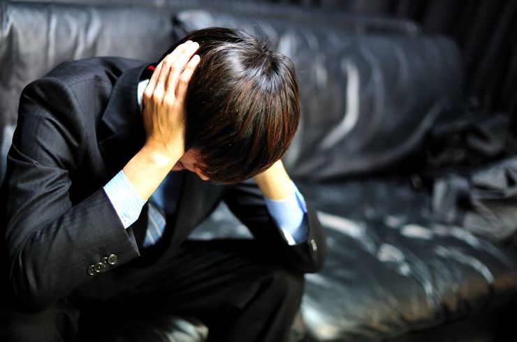 ソファーで悩む男性